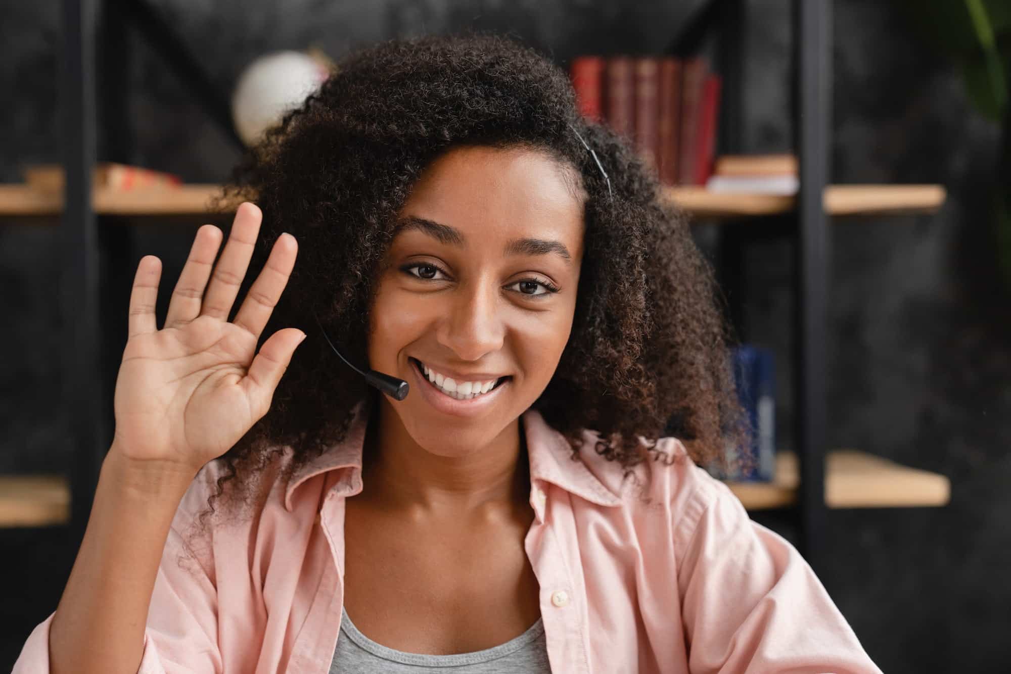 Bilingual customer support representative waving and smiling at the camera