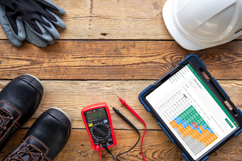 A property maintenance technician's tools, including boots, gloves, helmet, digital gauges, and tablet.