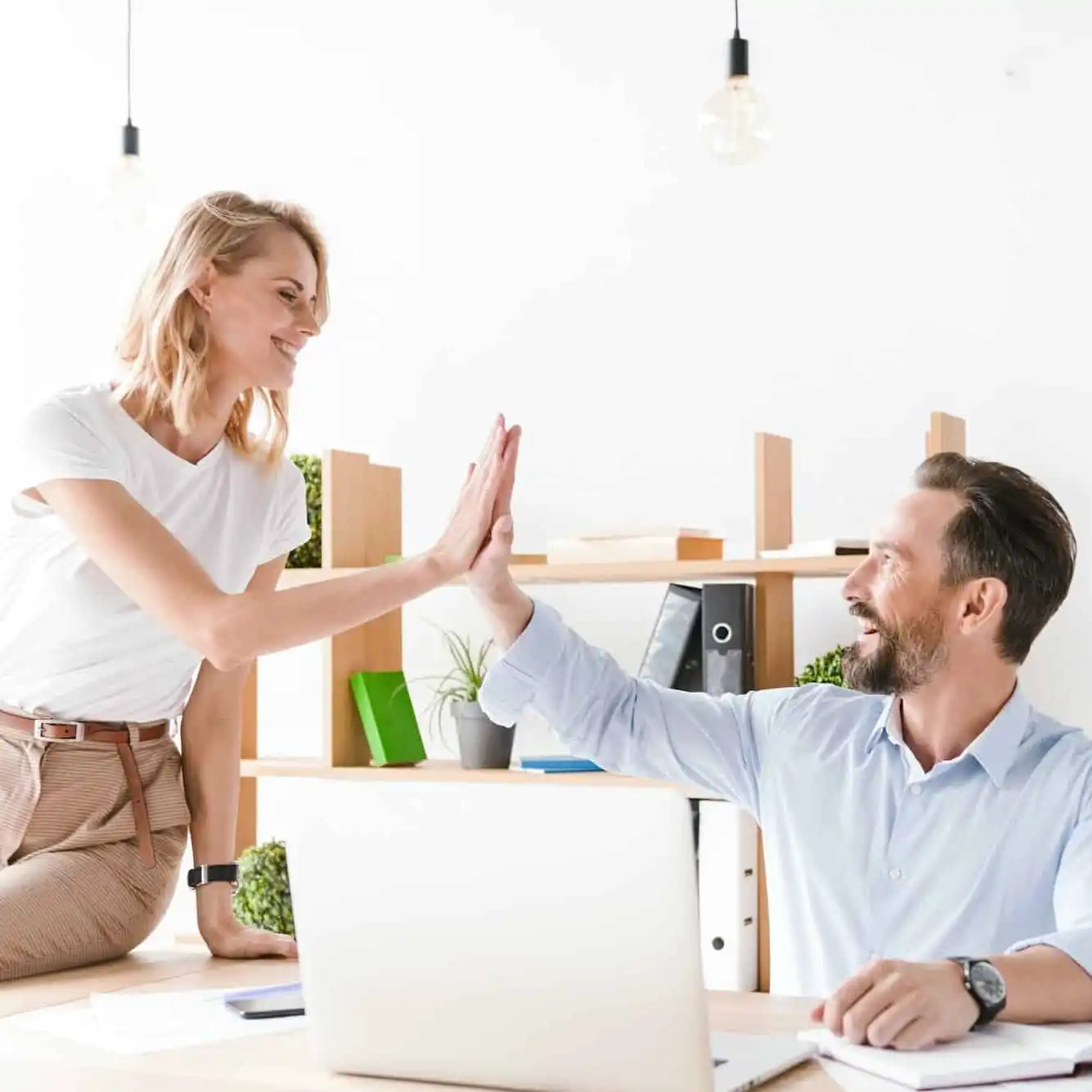 couple-of-excited-colleagues-giving-high-five-uai-1335x1335